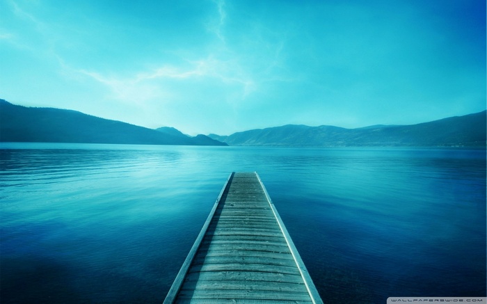 Wooden pier on a calm blue lake with mountains