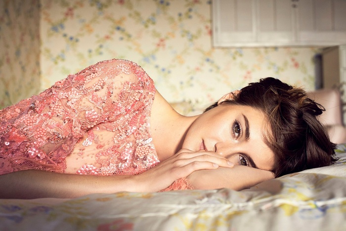 Shailene Woodley lying in bed wearing a pink dress