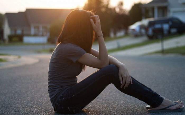 Woman sitting on a street at sunset