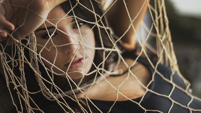 Woman with freckles behind a net