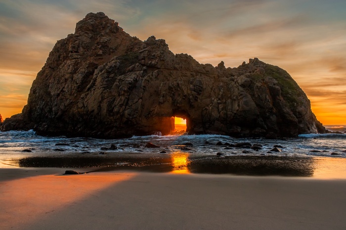 Rock archway on a beach at sunset