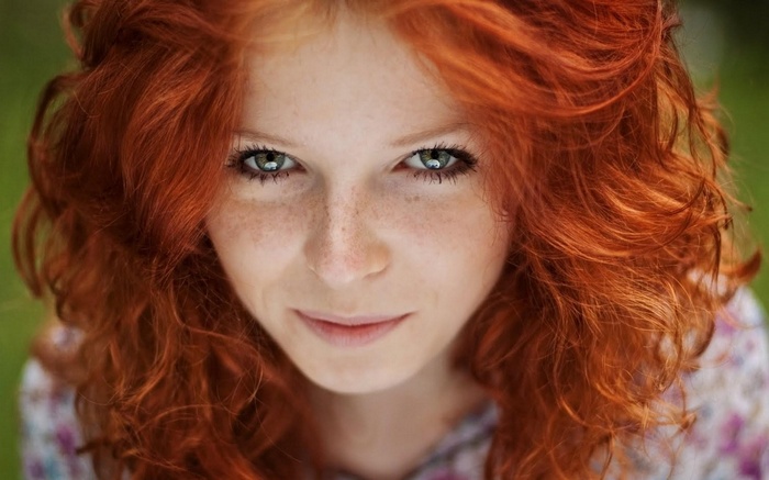 Close-up portrait of a young woman with red hair and freckles