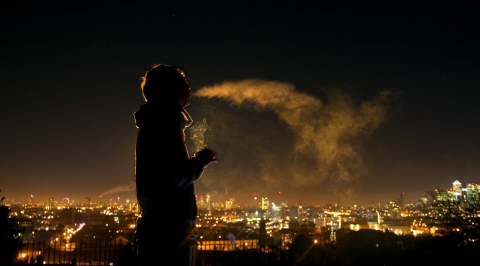Person smoking at night with city skyline