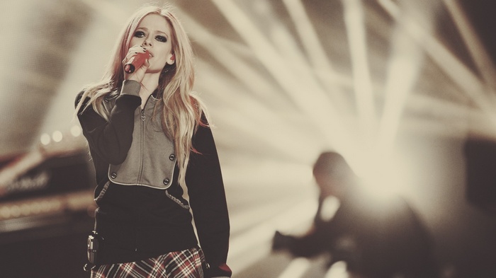 Avril Lavigne singing on stage with bright lights