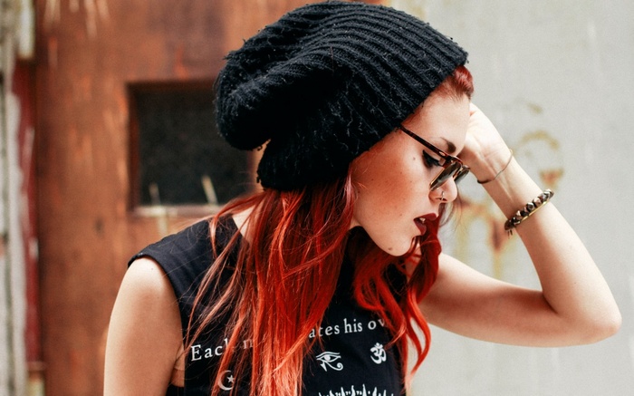Woman with red hair wearing a black beanie and sunglasses