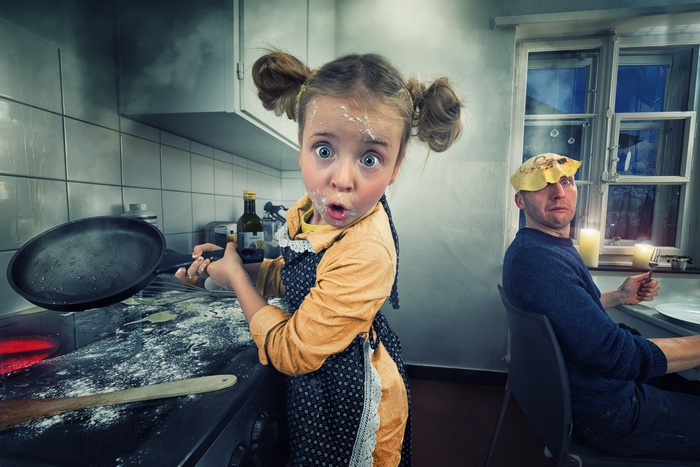 Messy kitchen with a surprised girl and a man with a pancake on his head