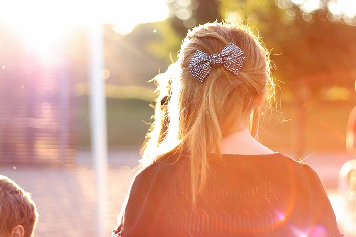 Woman with blonde hair and a sparkly bow in sunlight
