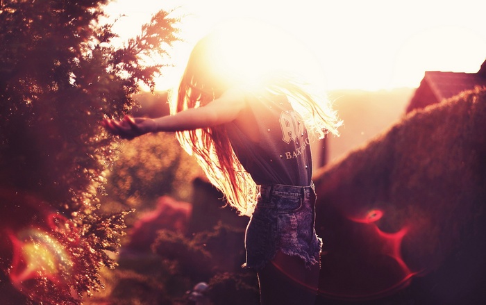 Woman with arms outstretched in sunlight