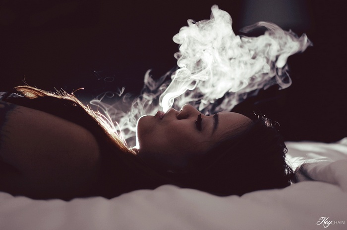 Woman lying down exhaling smoke