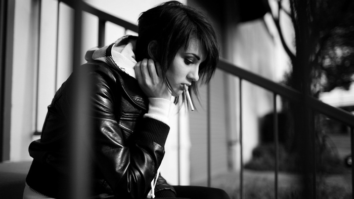 Sad woman smoking a cigarette on steps
