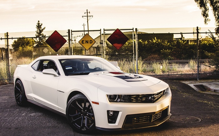 White Chevrolet Camaro ZL1 parked near railroad crossing signs