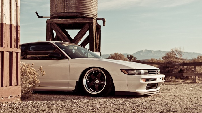 White Nissan Silvia S13 parked near a water tower