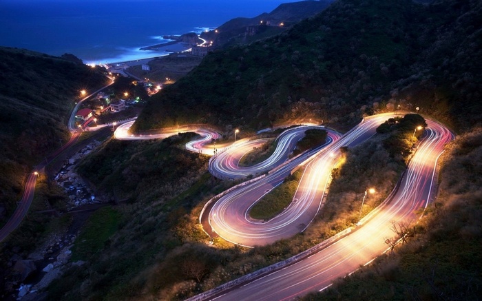 Mountain road with light trails at night