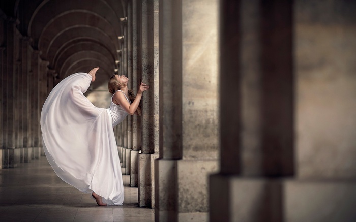 Woman in white dress dancing by pillars