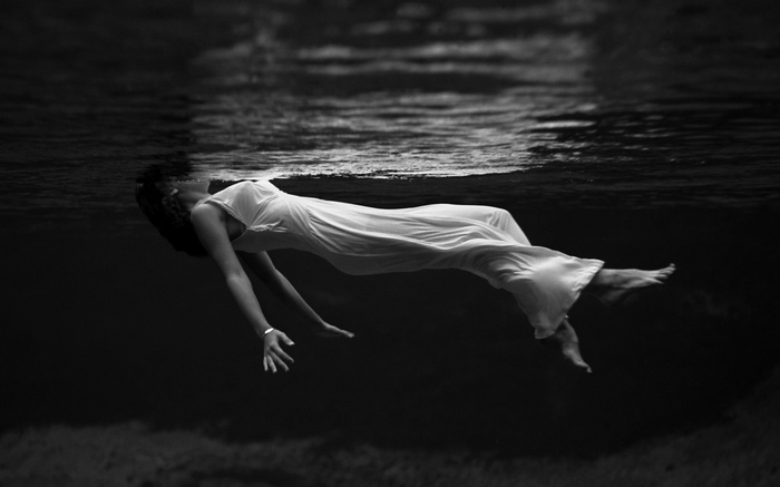 Woman in white dress floating underwater