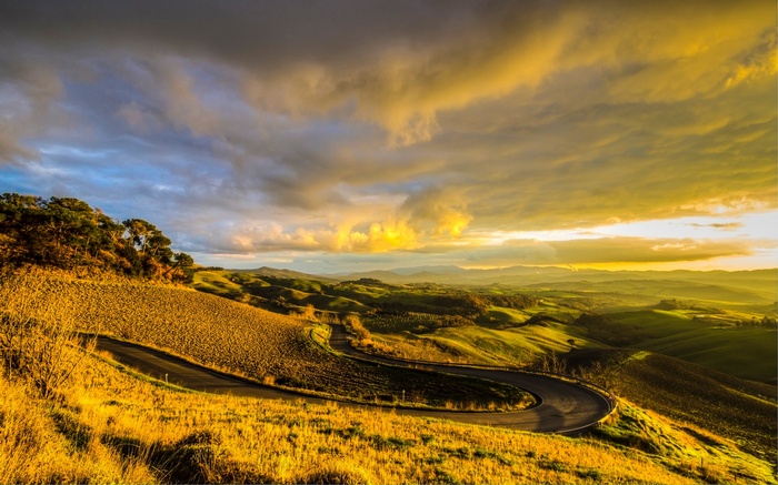Winding road through rolling hills in Tuscany at sunset