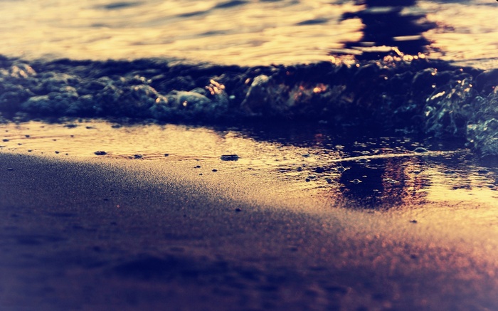 Waves crashing on a sandy beach at sunset
