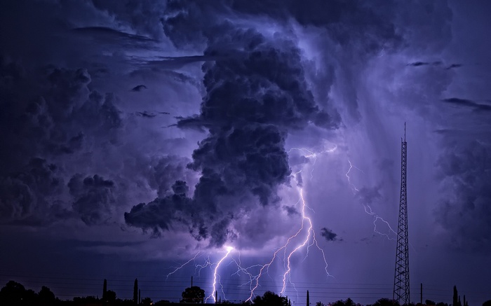 Lightning strikes during a powerful thunderstorm over a landscape.
