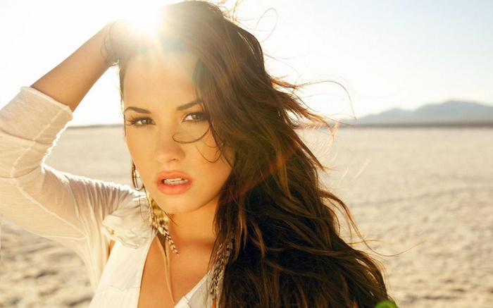 Demi Lovato in sunlight with hands on head