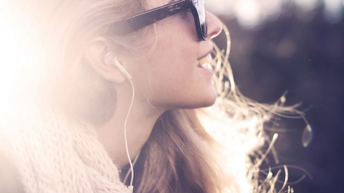 Woman wearing Ray-Ban sunglasses and earphones