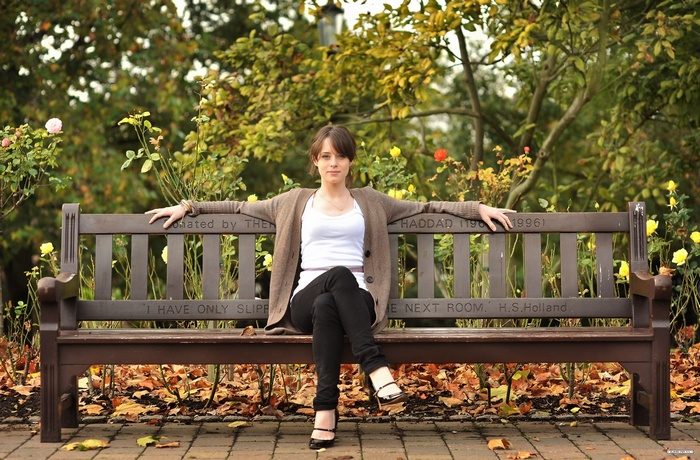 Claire Foy sitting on a park bench