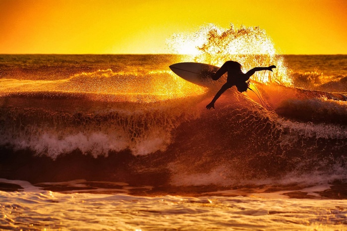 Surfer catches a wave at sunset