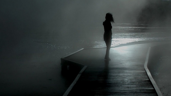 Silhouette of a person on a misty boardwalk