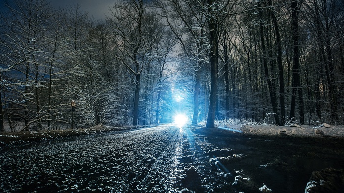 Fantasy art of a snowy forest road with bright lights