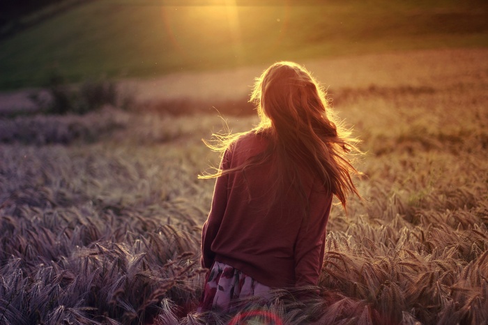 Woman with long hair in a field at sunset