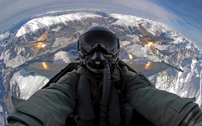 Pilot in a jet fighter flying over snowy mountains