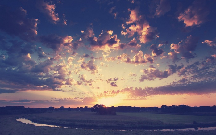 Sunset over a river and fields with dramatic clouds
