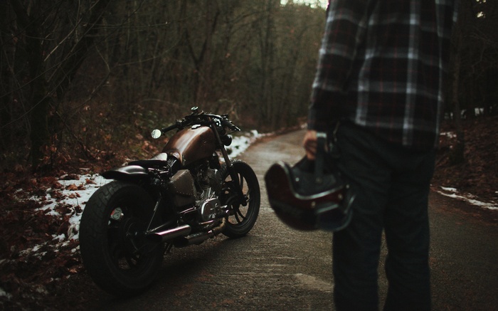 Man holding helmet next to a custom Bobber motorcycle