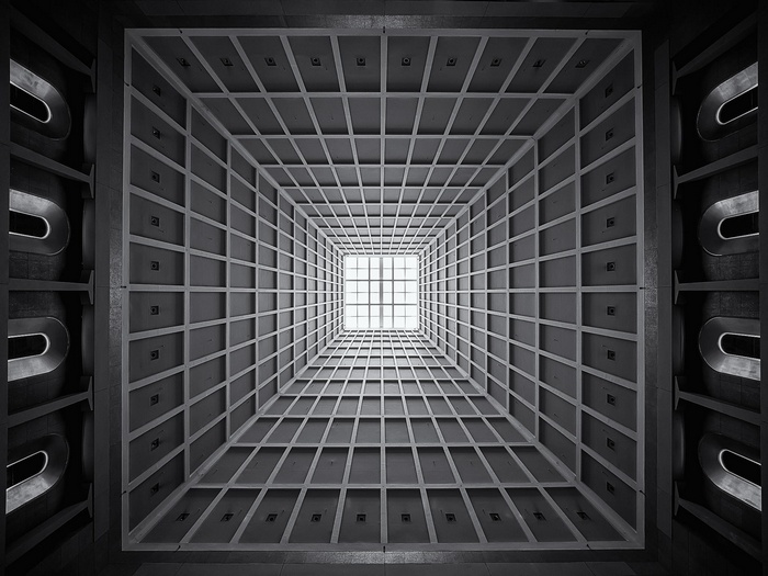Monochrome building interior with geometric ceiling and skylight