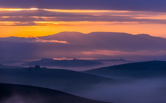 Tuscan landscape at sunset with rolling hills and mist