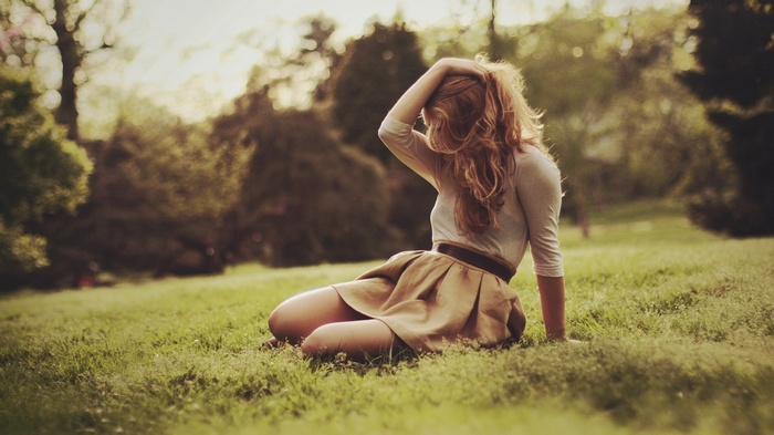 Woman with long hair sitting in a grassy park