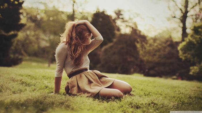 Woman in skirt sitting on grass outdoors