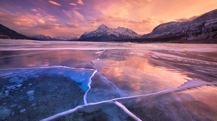 Frozen lake with mountains at sunset