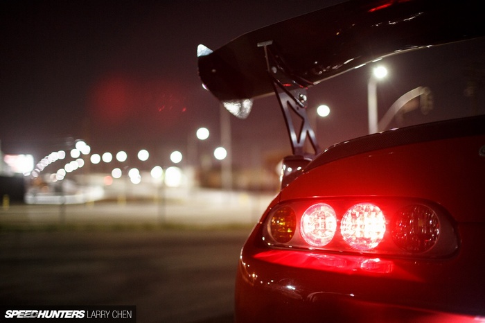 Red Toyota Supra with large spoiler at night