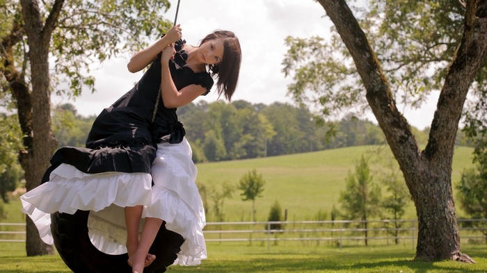 Woman in black and white dress on tire swing