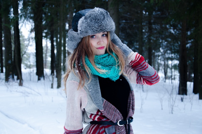 Woman in winter hat and scarf in snowy forest