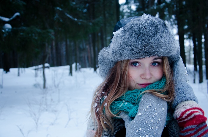 Woman in a fur hat and scarf in a snowy forest