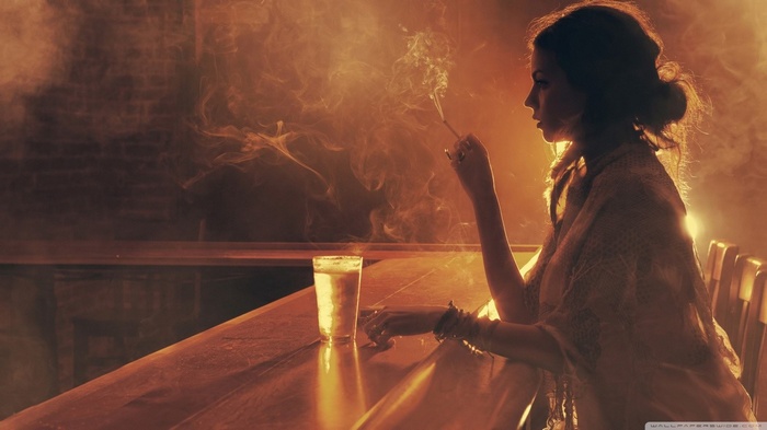 Woman smoking at a bar with a drink