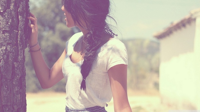 Woman with braided hair leaning on a tree