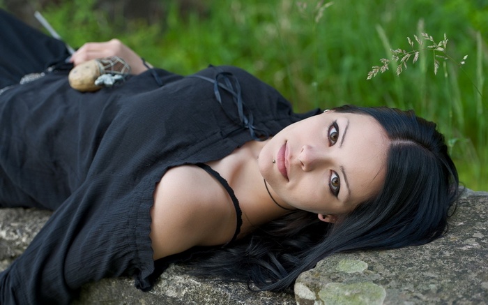 Woman with dark hair lying on rocks outdoors