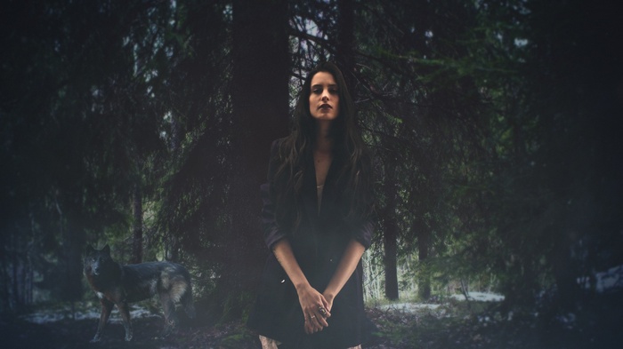 Woman and wolf in a dark forest