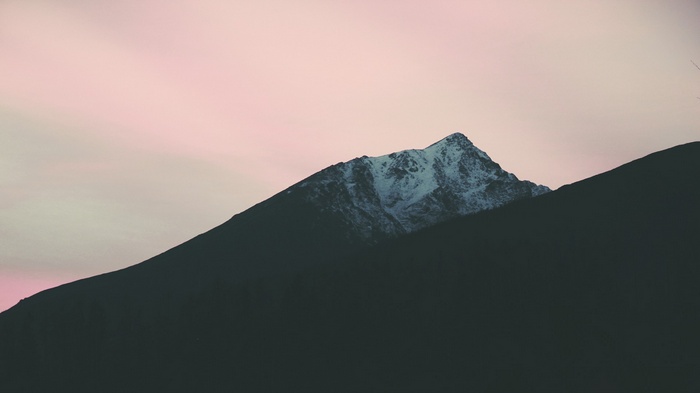 Snow-capped mountain peak against a pink sky