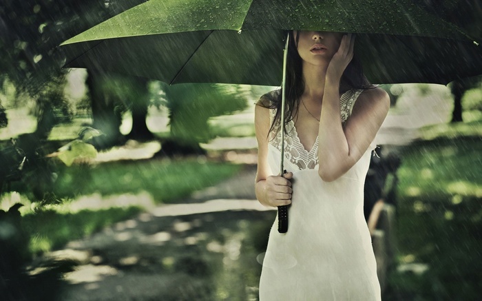 Woman in white dress holding an umbrella in the rain