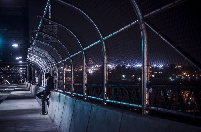 Woman on a bridge overlooking a cityscape at night