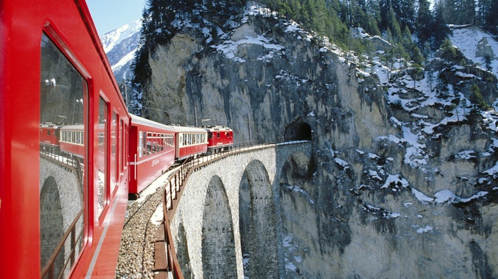 Red train on a bridge in the Swiss Alps