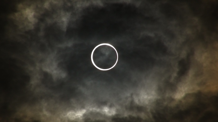 Solar eclipse seen through dark clouds
